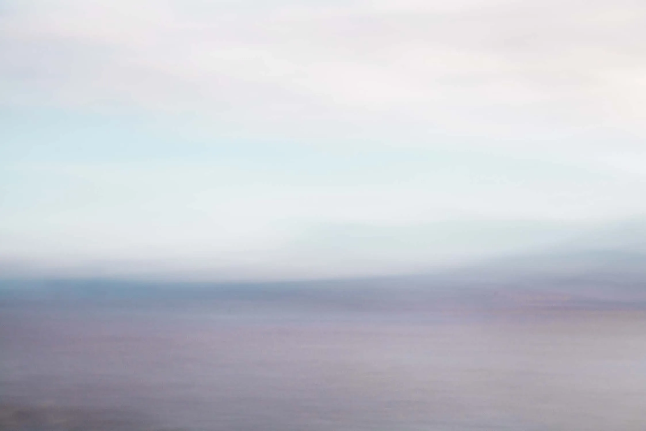 Mare e cielo sfocati in tonalità pastello, azzurro e lilla.