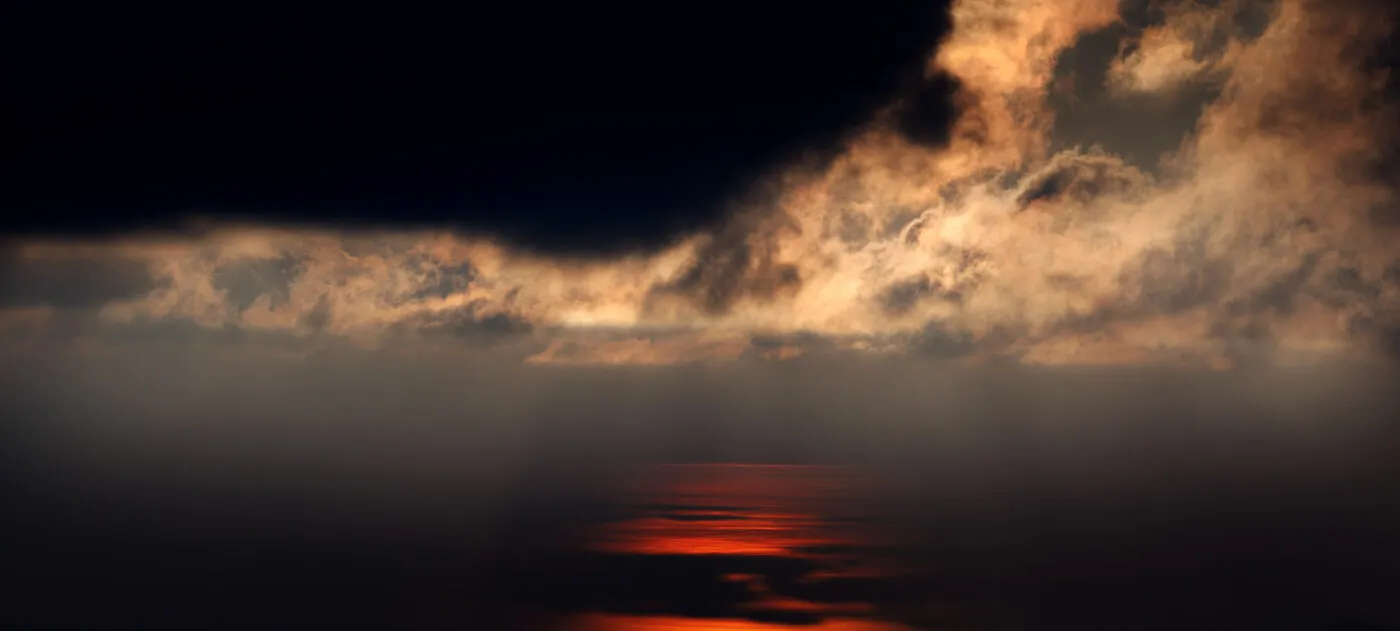 Nuvole dorate contro un cielo scuro, riflesso rosso sul mare.